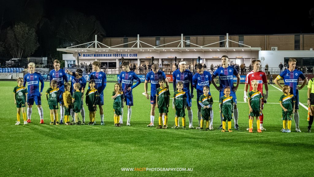 Manly United line up with mascots from Curl Curl before their 2023 NPL NSW Men's Round 23 game against Marconi Stallions at Cromer Park. Photo credit: Jeremy Denham