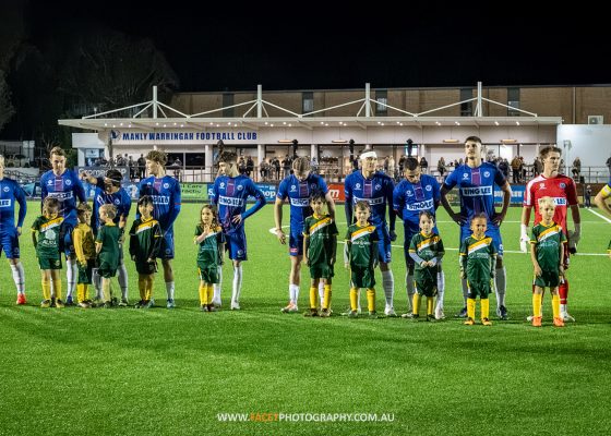 Manly United line up with mascots from Curl Curl before their 2023 NPL NSW Men's Round 23 game against Marconi Stallions at Cromer Park. Photo credit: Jeremy Denham