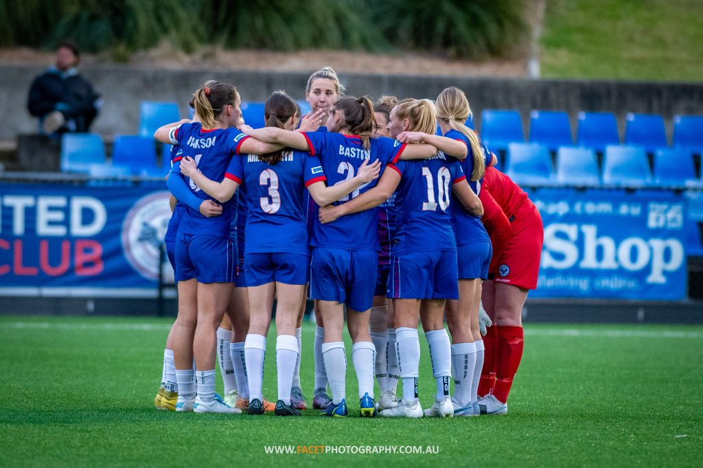 Manly United huddle before their 2023 NPL NSW Women's Round 23 game against NWS Spirit at Cromer Park. Photo credit: Jeremy Denham